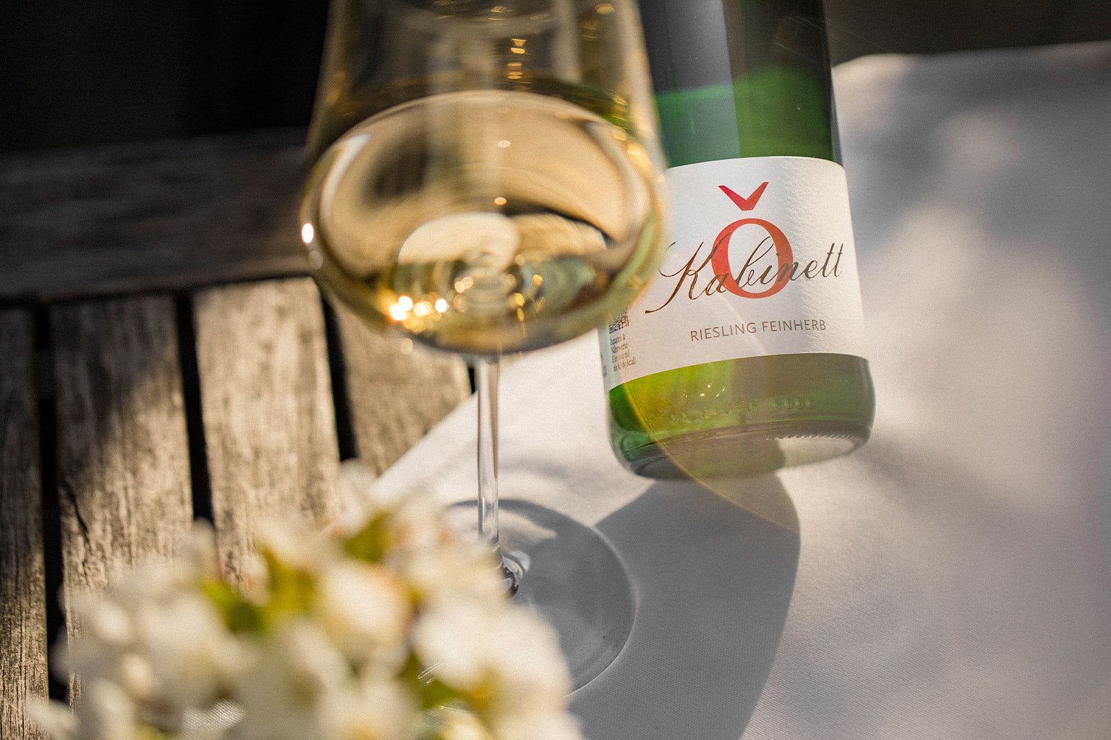 Moselwein Riesling feinherb vom Weingut von Othegraven im Glas mit Weinflasche im Hintergrund